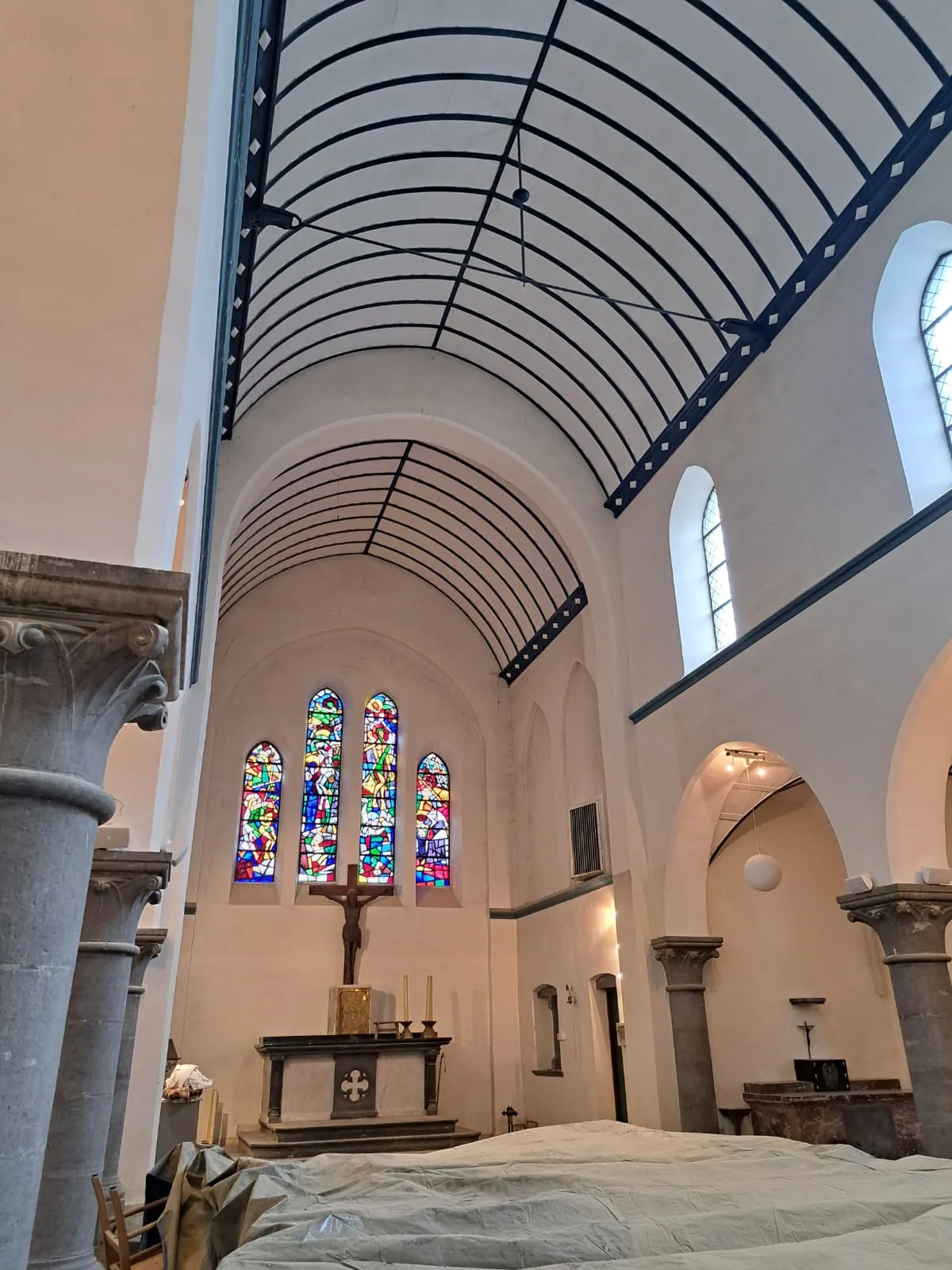 Nef d'église aux murs enduits à la chaux blanche, colonnes de pierre et vitraux