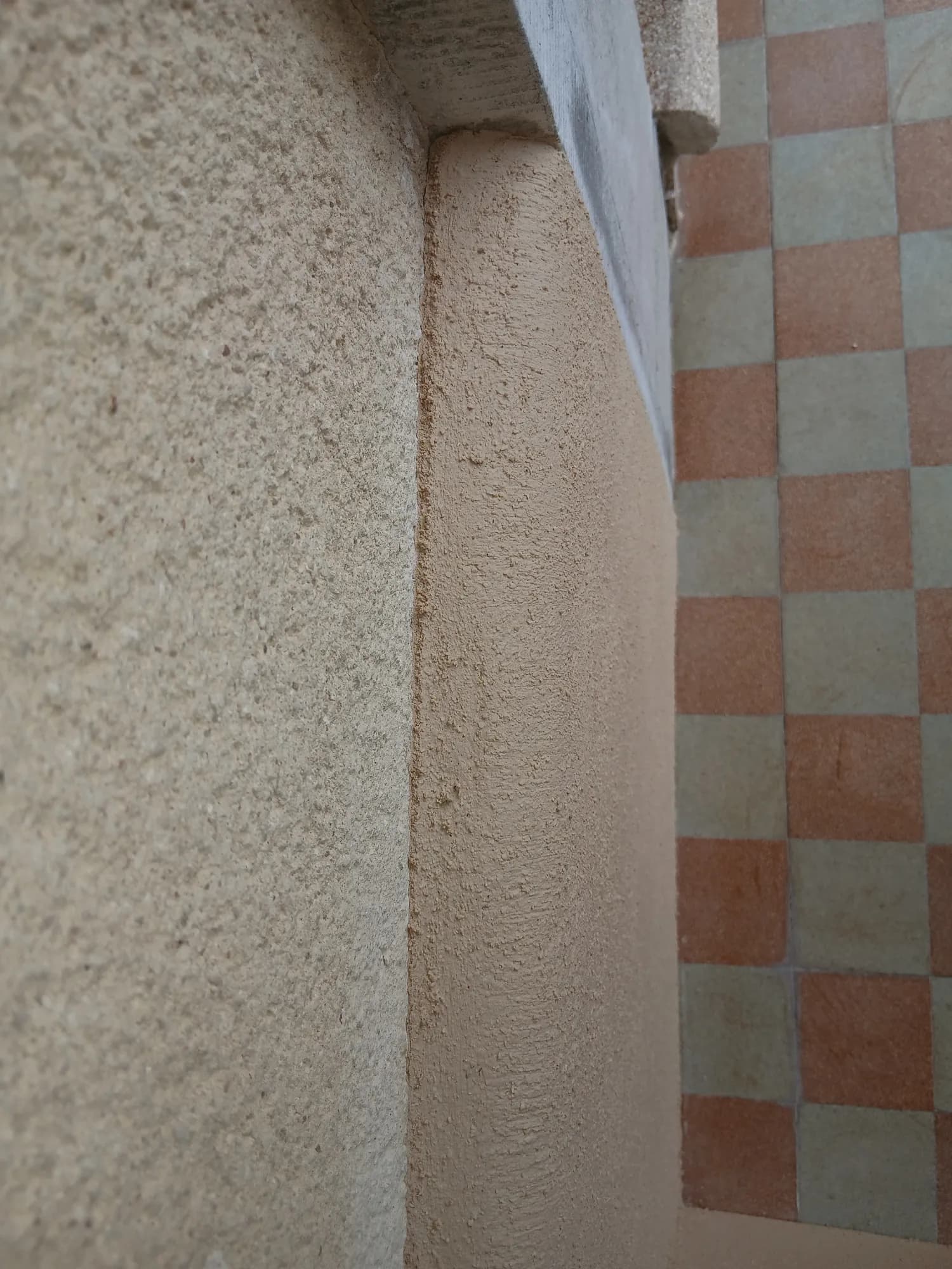 Entrée d'une maison ancienne au carrelage damier, murs et brique enduits à la chaux