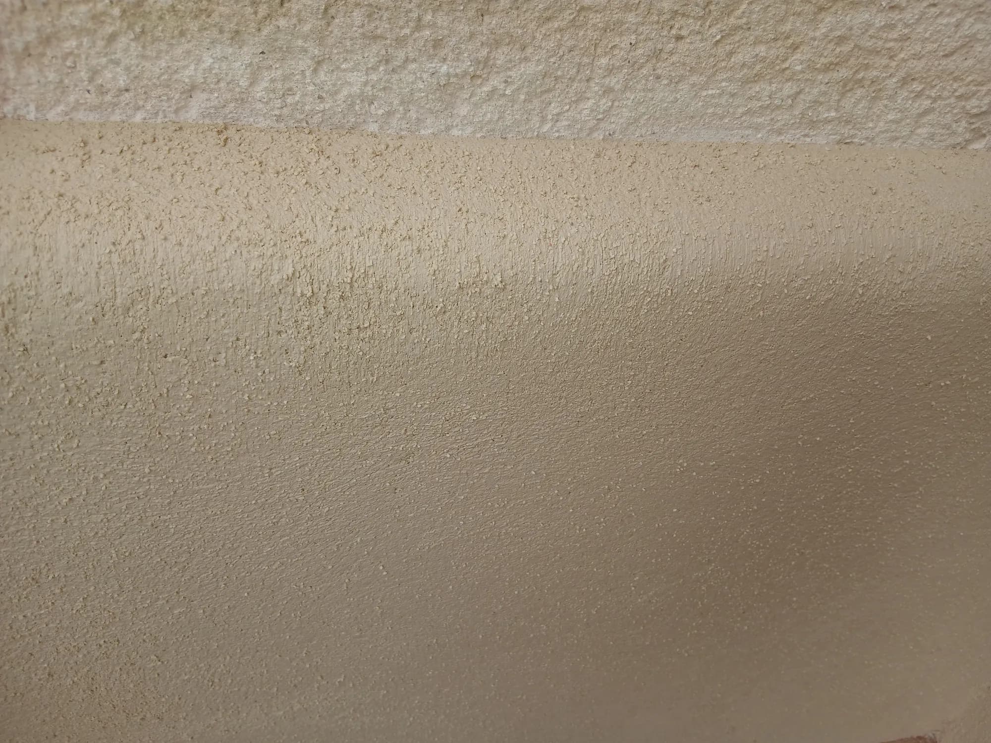 Gros plan sur la texture finement grainée d'un enduit à la chaux